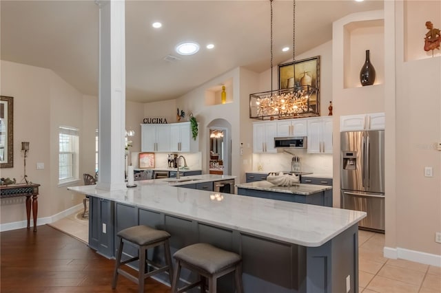 kitchen featuring light stone countertops, a spacious island, white cabinetry, and appliances with stainless steel finishes