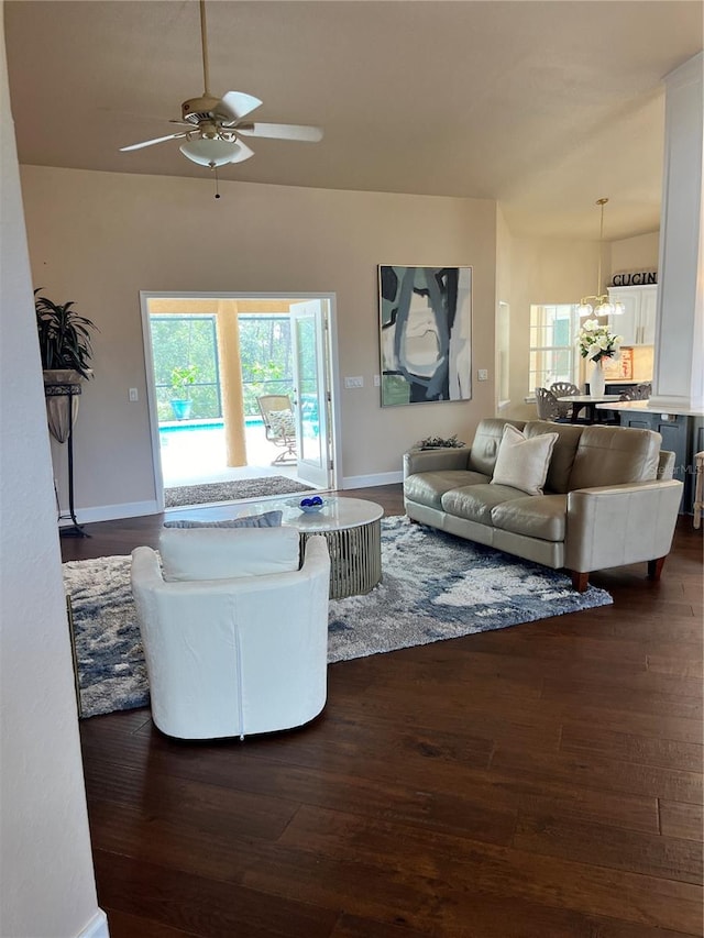 living room with ceiling fan with notable chandelier and dark hardwood / wood-style floors