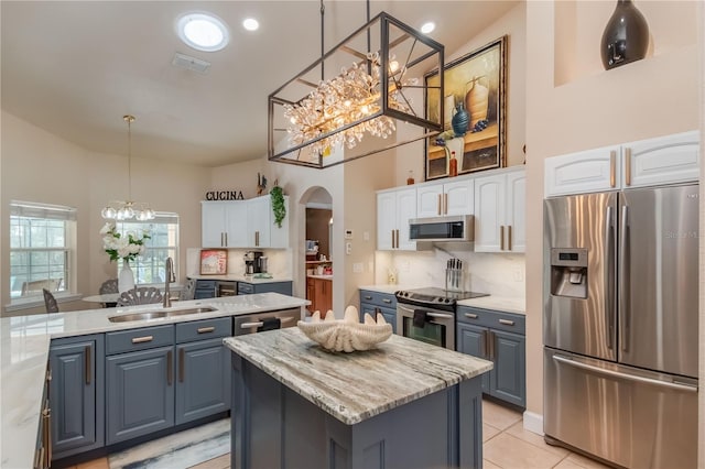 kitchen featuring stainless steel appliances, sink, decorative light fixtures, a center island with sink, and white cabinetry