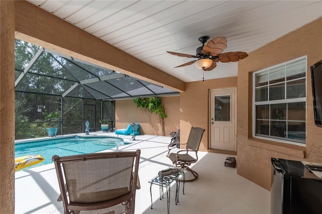 view of swimming pool with glass enclosure, ceiling fan, and a patio