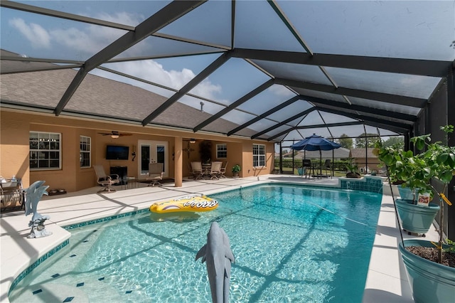 view of swimming pool featuring glass enclosure, a patio area, french doors, and ceiling fan