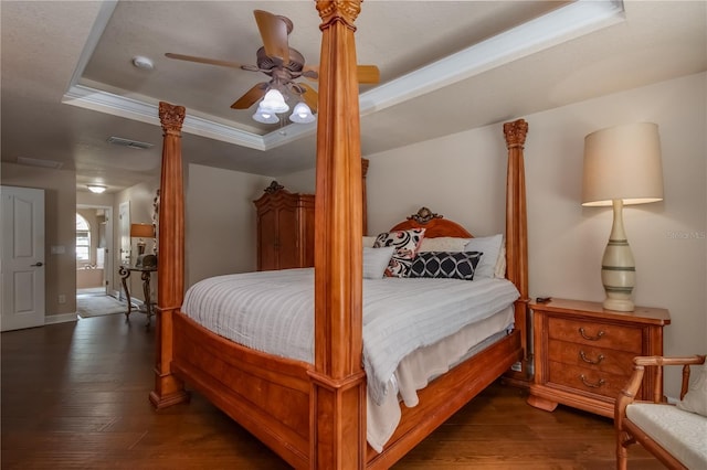 bedroom featuring ceiling fan, dark hardwood / wood-style flooring, a raised ceiling, and crown molding