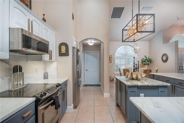 kitchen featuring white cabinets, decorative light fixtures, light tile patterned floors, a notable chandelier, and stainless steel appliances