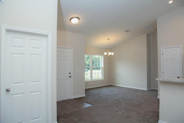 carpeted spare room with a notable chandelier