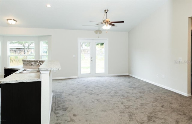 unfurnished living room featuring french doors, a healthy amount of sunlight, ceiling fan, and dark carpet