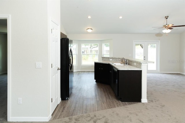 kitchen with plenty of natural light, an island with sink, ceiling fan, and black fridge