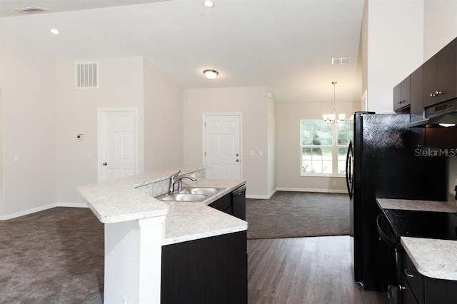 kitchen with a kitchen island with sink, sink, hanging light fixtures, a chandelier, and dark wood-type flooring