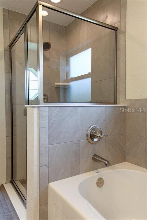 bathroom with tile walls, hardwood / wood-style floors, and independent shower and bath