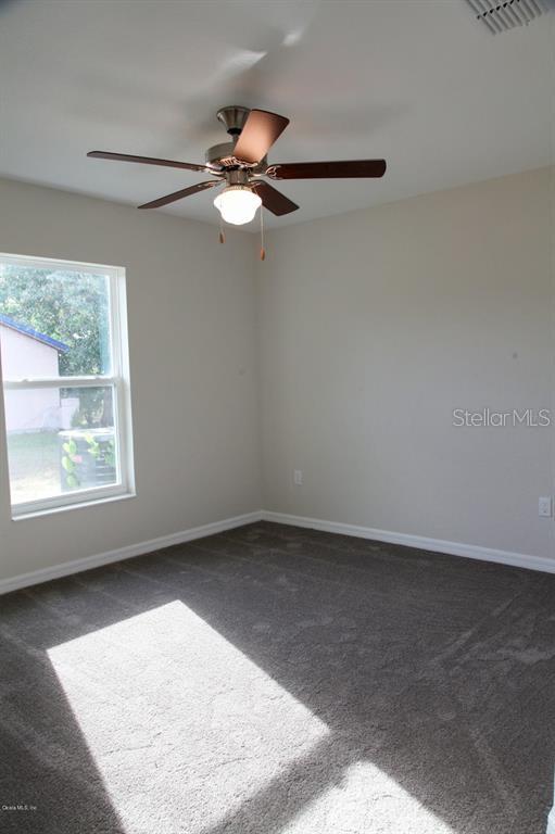 carpeted empty room featuring ceiling fan