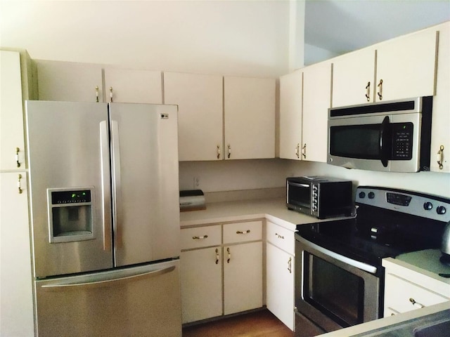 kitchen with white cabinets, dark wood-type flooring, and appliances with stainless steel finishes