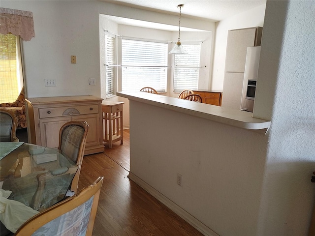 kitchen featuring hardwood / wood-style floors, stainless steel fridge with ice dispenser, and pendant lighting