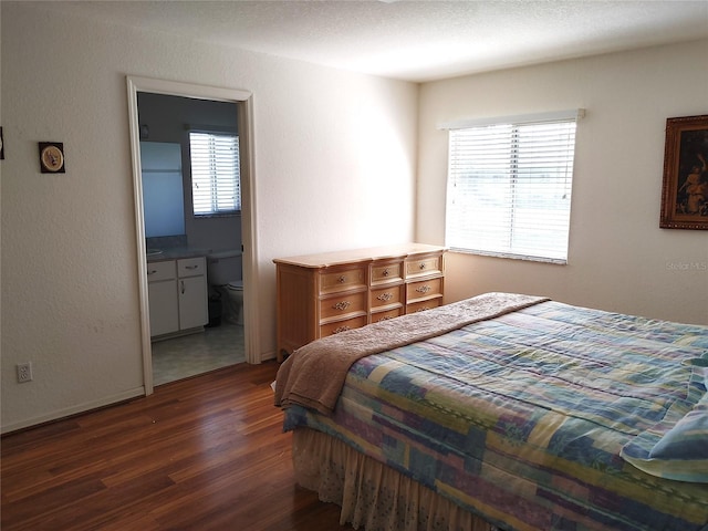 bedroom with dark hardwood / wood-style floors and ensuite bathroom