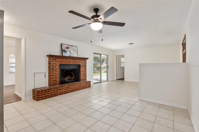 unfurnished living room featuring ceiling fan, a textured ceiling, light tile patterned floors, and a fireplace