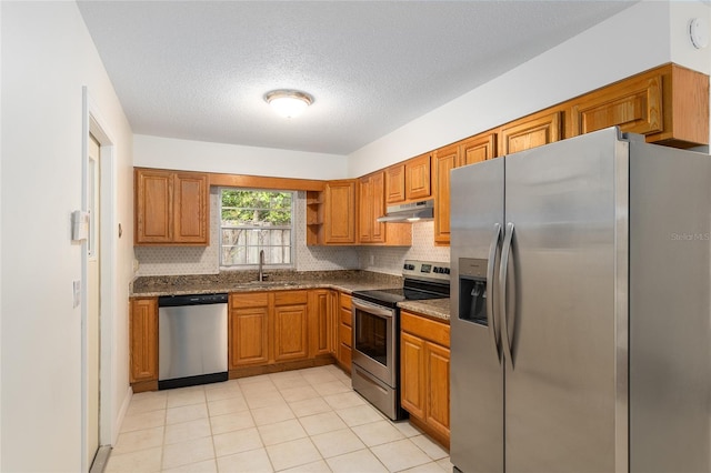 kitchen featuring dark stone countertops, decorative backsplash, sink, appliances with stainless steel finishes, and a textured ceiling