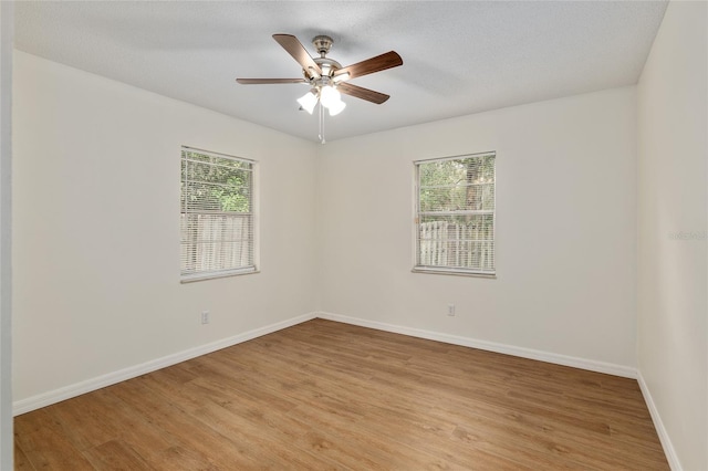 spare room featuring light hardwood / wood-style floors, a textured ceiling, ceiling fan, and a healthy amount of sunlight