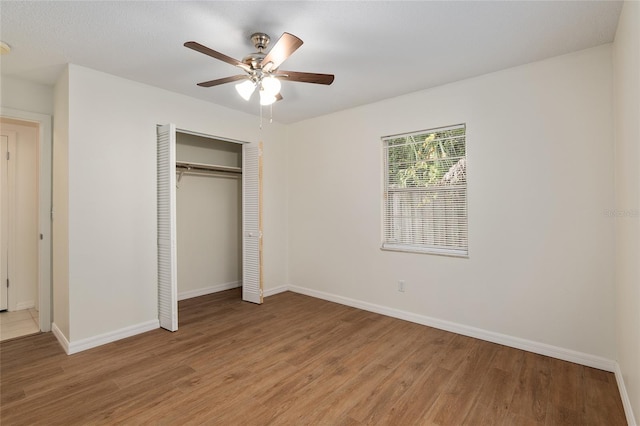 unfurnished bedroom with ceiling fan, hardwood / wood-style flooring, and a closet