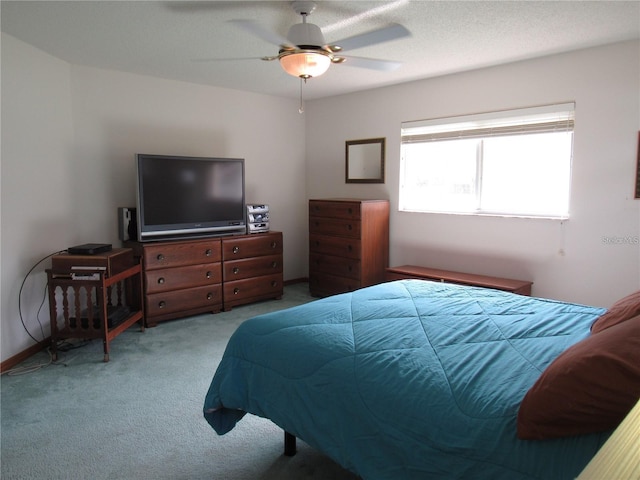 carpeted bedroom with ceiling fan and a textured ceiling