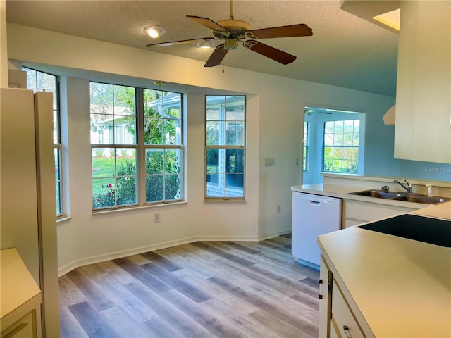 kitchen featuring dishwasher, sink, a textured ceiling, light hardwood / wood-style floors, and stainless steel refrigerator