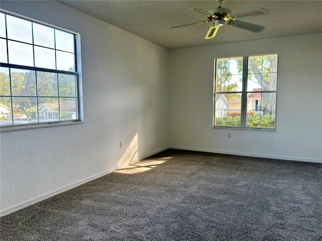 spare room with ceiling fan and dark colored carpet