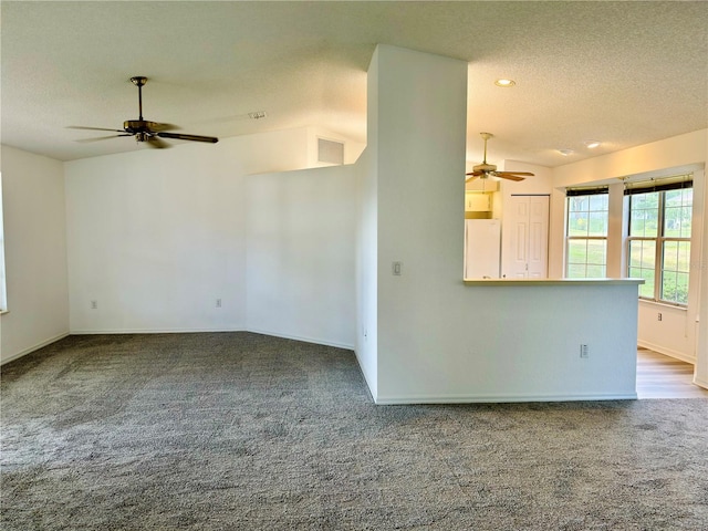 unfurnished living room featuring a textured ceiling, ceiling fan, and carpet floors