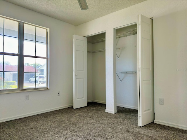 unfurnished bedroom featuring multiple windows, carpet floors, a textured ceiling, and ceiling fan