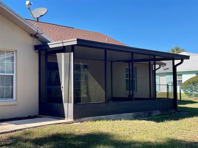 view of side of home featuring a sunroom and a lawn