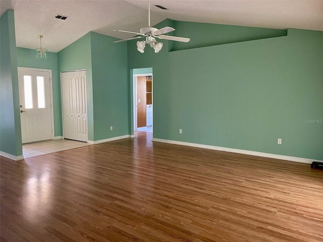 unfurnished room with a textured ceiling, light hardwood / wood-style flooring, high vaulted ceiling, and ceiling fan with notable chandelier