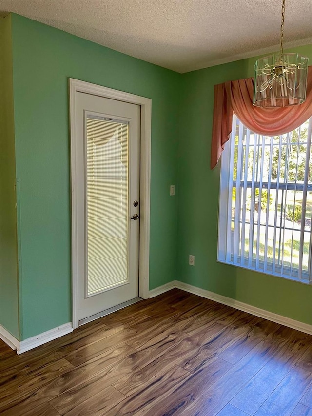 unfurnished room with dark hardwood / wood-style flooring, a textured ceiling, and a chandelier