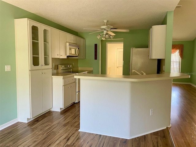 kitchen with white appliances, white cabinets, dark hardwood / wood-style floors, and ceiling fan