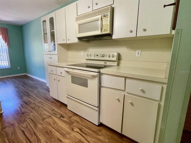 kitchen featuring white appliances, a textured ceiling, white cabinetry, and dark hardwood / wood-style flooring