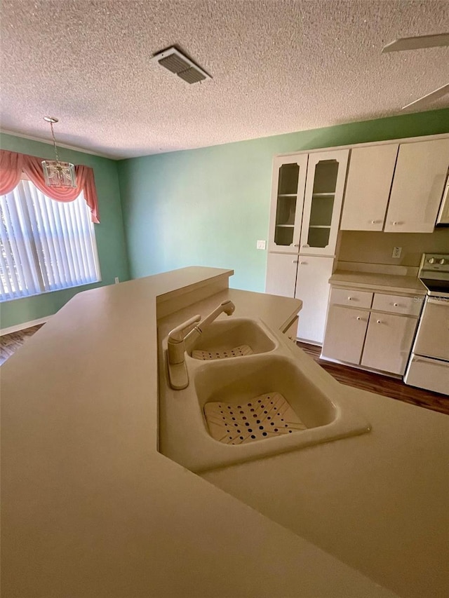 interior space featuring white range with electric cooktop, a textured ceiling, decorative light fixtures, and white cabinetry