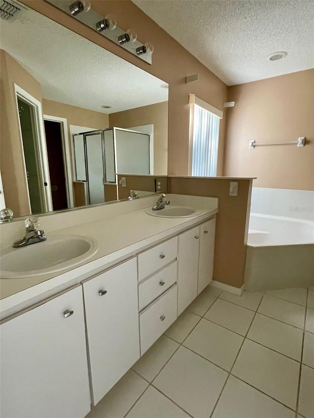 bathroom with tile flooring, double sink, a textured ceiling, a bathing tub, and large vanity