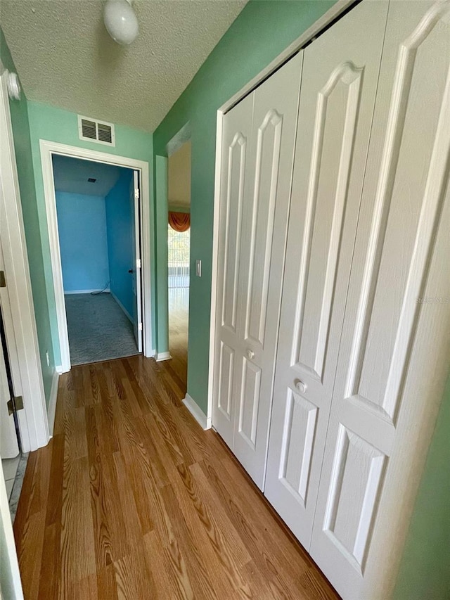 hall featuring light hardwood / wood-style flooring and a textured ceiling