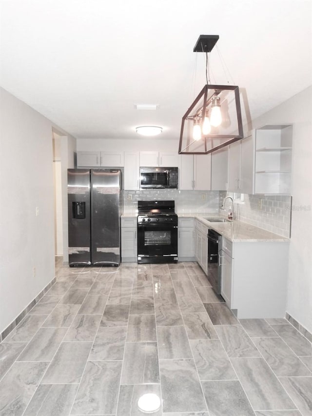 kitchen with light stone countertops, backsplash, black appliances, sink, and pendant lighting