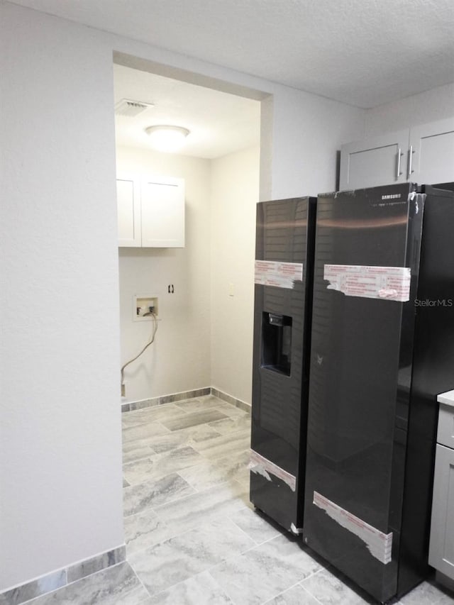 kitchen featuring black fridge with ice dispenser and white cabinetry