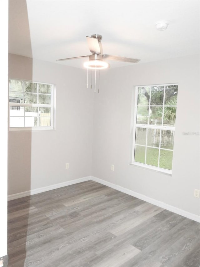 spare room featuring plenty of natural light, ceiling fan, and dark hardwood / wood-style flooring