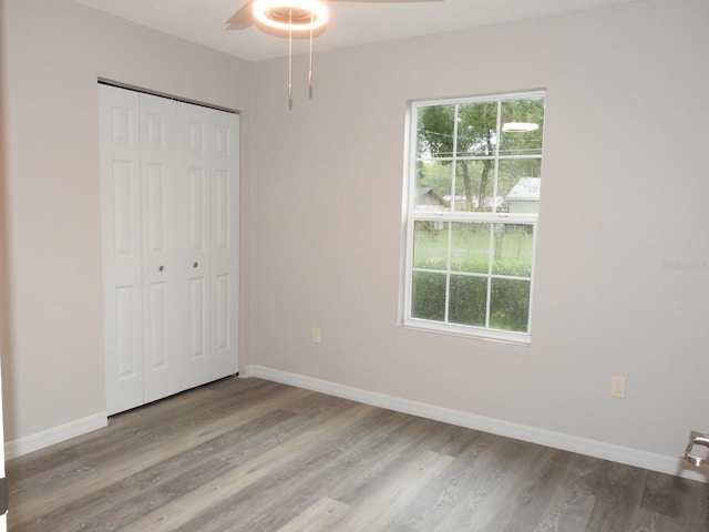 unfurnished bedroom featuring ceiling fan, a closet, light hardwood / wood-style floors, and multiple windows