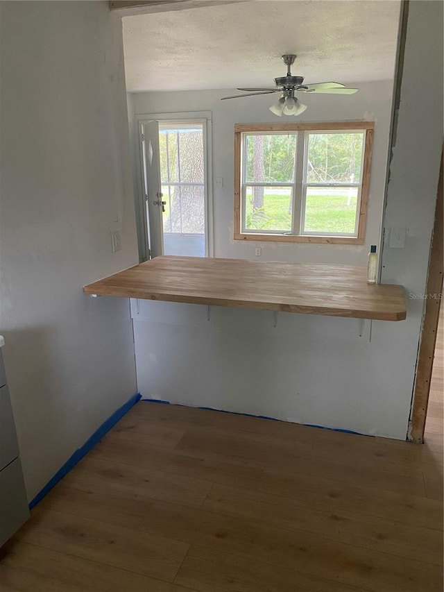 kitchen with kitchen peninsula, a breakfast bar area, wooden counters, ceiling fan, and hardwood / wood-style flooring