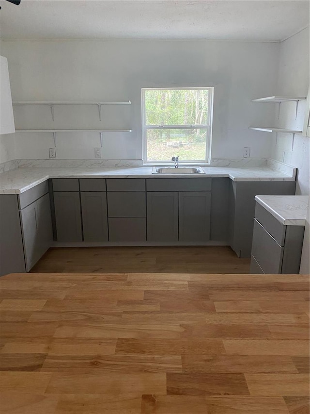 kitchen featuring washer / clothes dryer, gray cabinets, light hardwood / wood-style floors, and sink