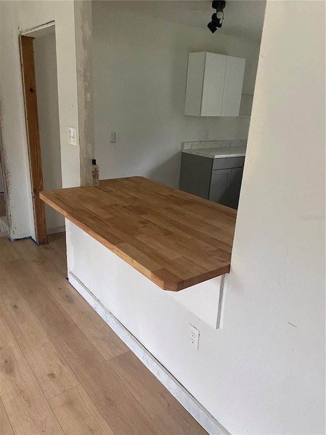 kitchen with butcher block countertops, light hardwood / wood-style floors, and white cabinetry