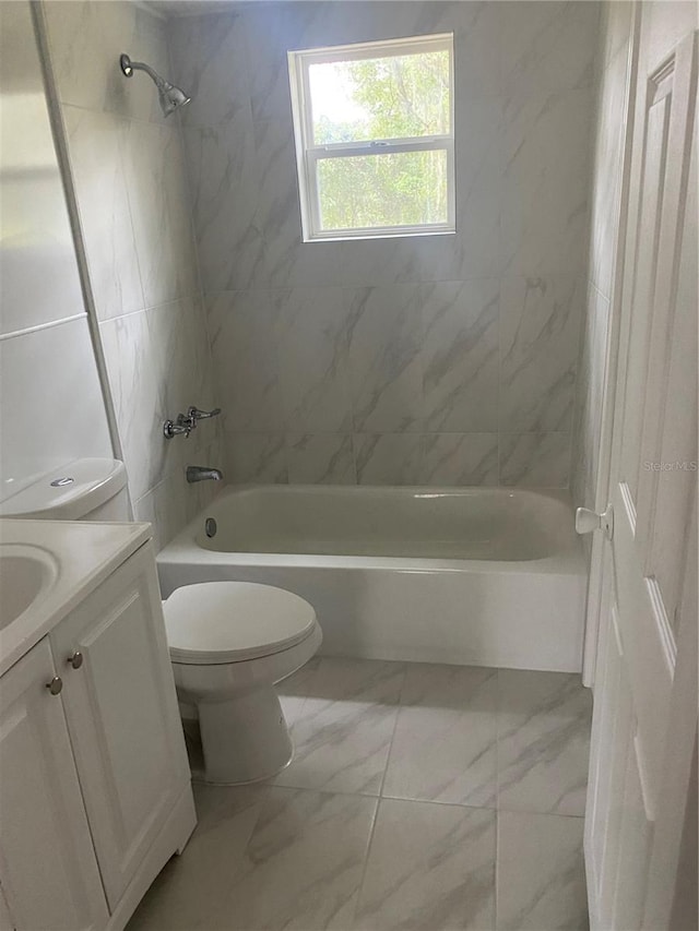 full bathroom featuring tiled shower / bath, vanity, and toilet