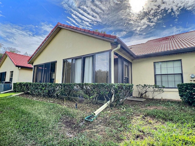 view of side of property with central AC and a yard