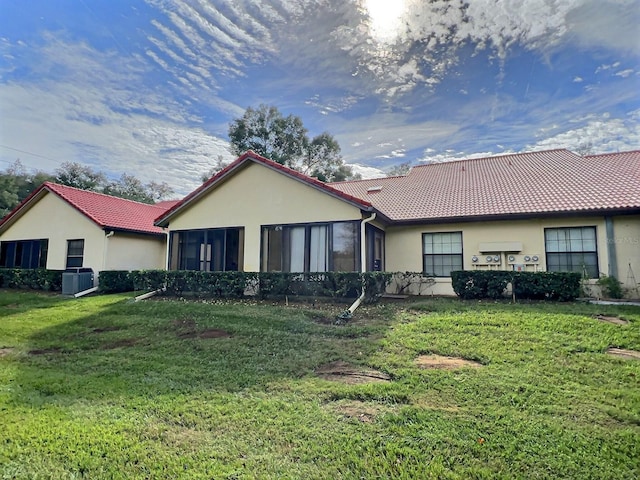 back of house featuring a lawn and central air condition unit