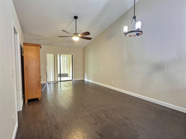 spare room with vaulted ceiling, dark wood-type flooring, and ceiling fan with notable chandelier