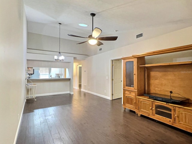 unfurnished living room featuring vaulted ceiling, dark wood-type flooring, and ceiling fan with notable chandelier