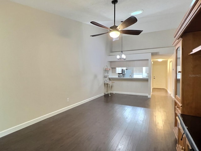 unfurnished living room featuring ceiling fan with notable chandelier and dark hardwood / wood-style flooring