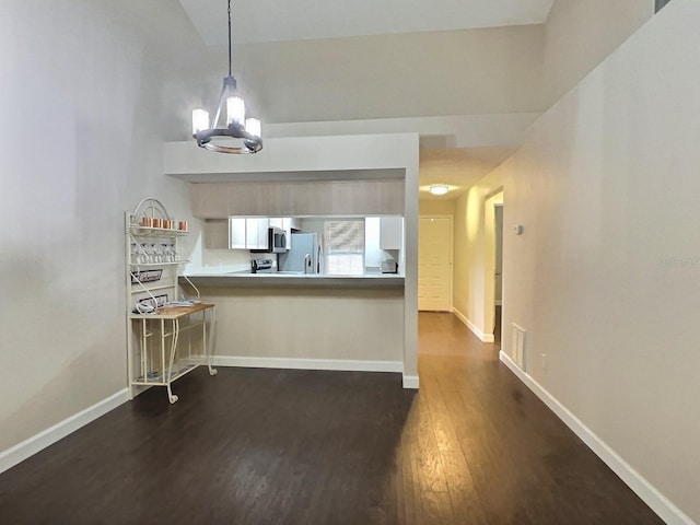 kitchen featuring kitchen peninsula, decorative light fixtures, dark hardwood / wood-style floors, an inviting chandelier, and appliances with stainless steel finishes