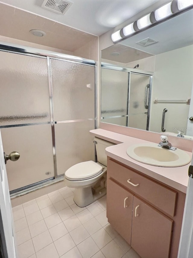 bathroom with oversized vanity, toilet, tile floors, and a shower with door