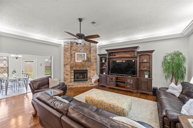 living room featuring a textured ceiling, ceiling fan with notable chandelier, hardwood / wood-style flooring, and a fireplace