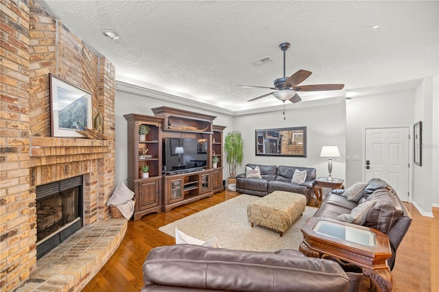 living room featuring a textured ceiling, ceiling fan, dark hardwood / wood-style flooring, and a fireplace